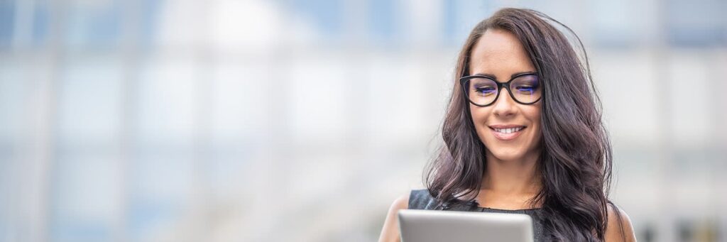 Female government employee holding a tablet in front of a building.