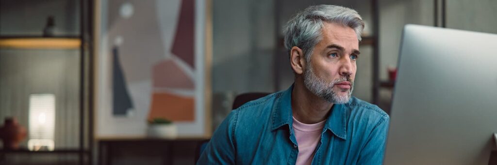 A middle-aged man focused on his computer monitor