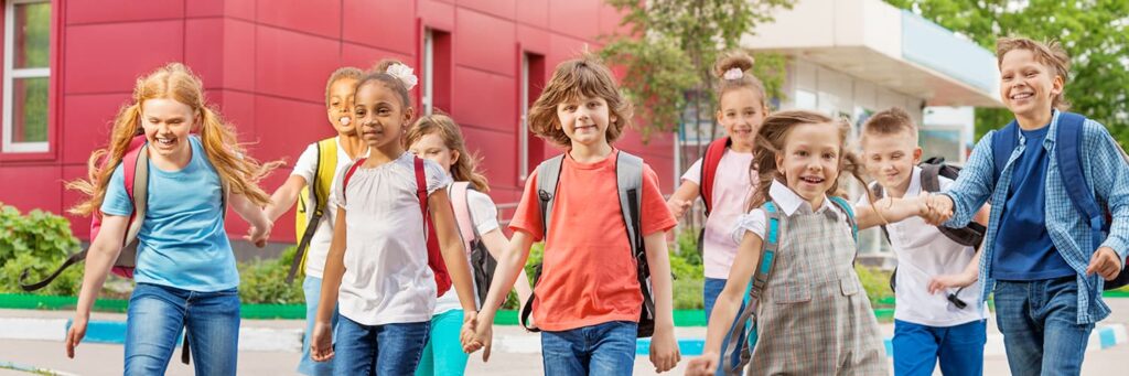 A group of happy children leaving a red school building