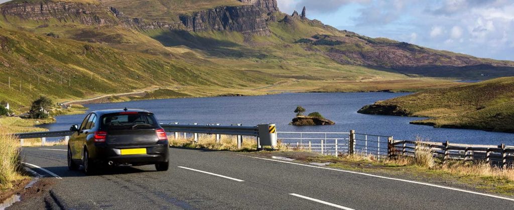 A car driving on a winding road next to water