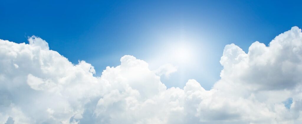 A bright sun and white clouds against a blue sky backdrop