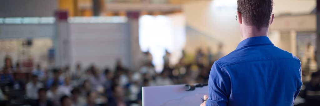 Man standing at a podium speaking during a school board meeting.